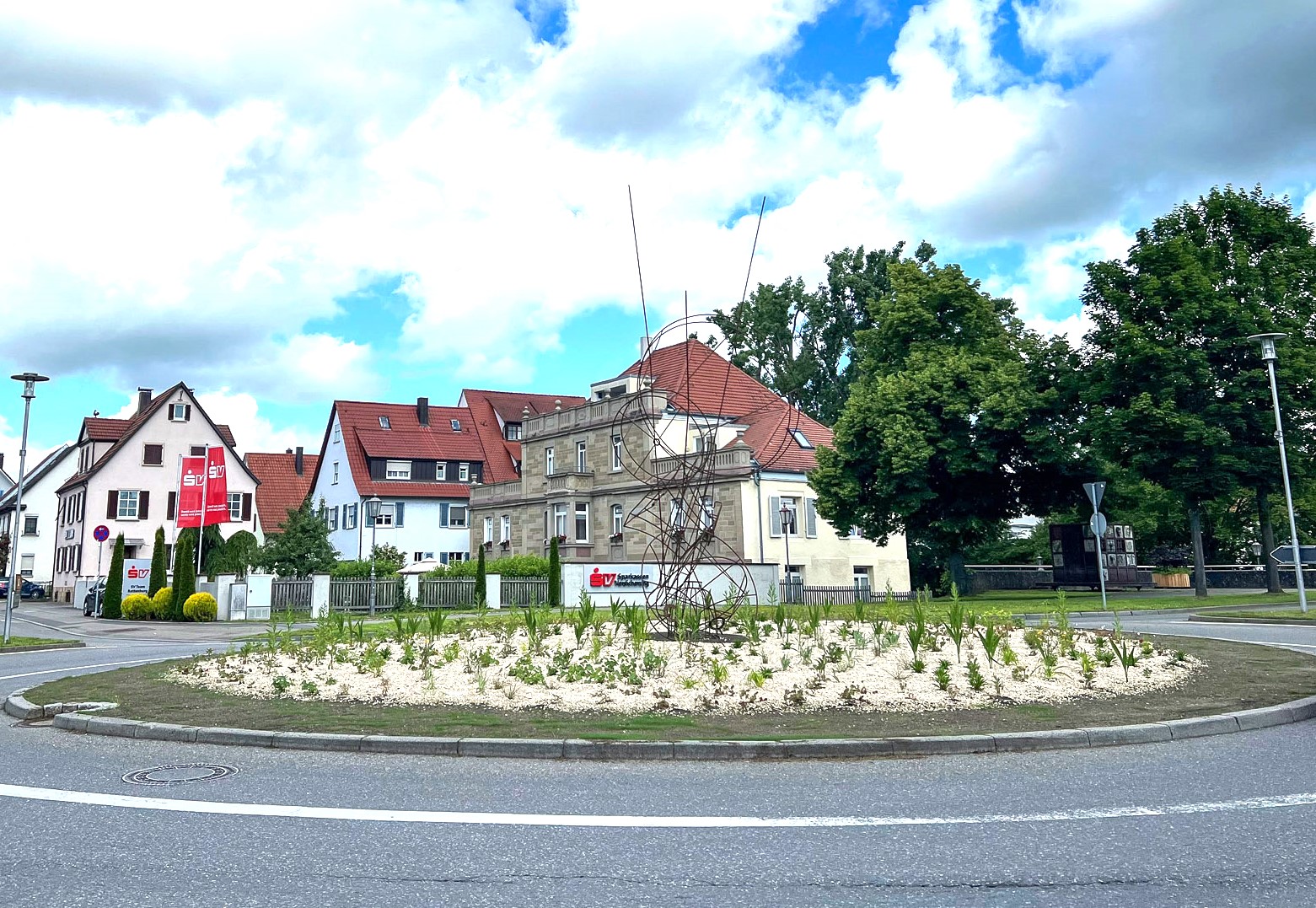 Ein Kreisverkehr mit Bepflanzung und einem Kunstwerk aus Metallstäben