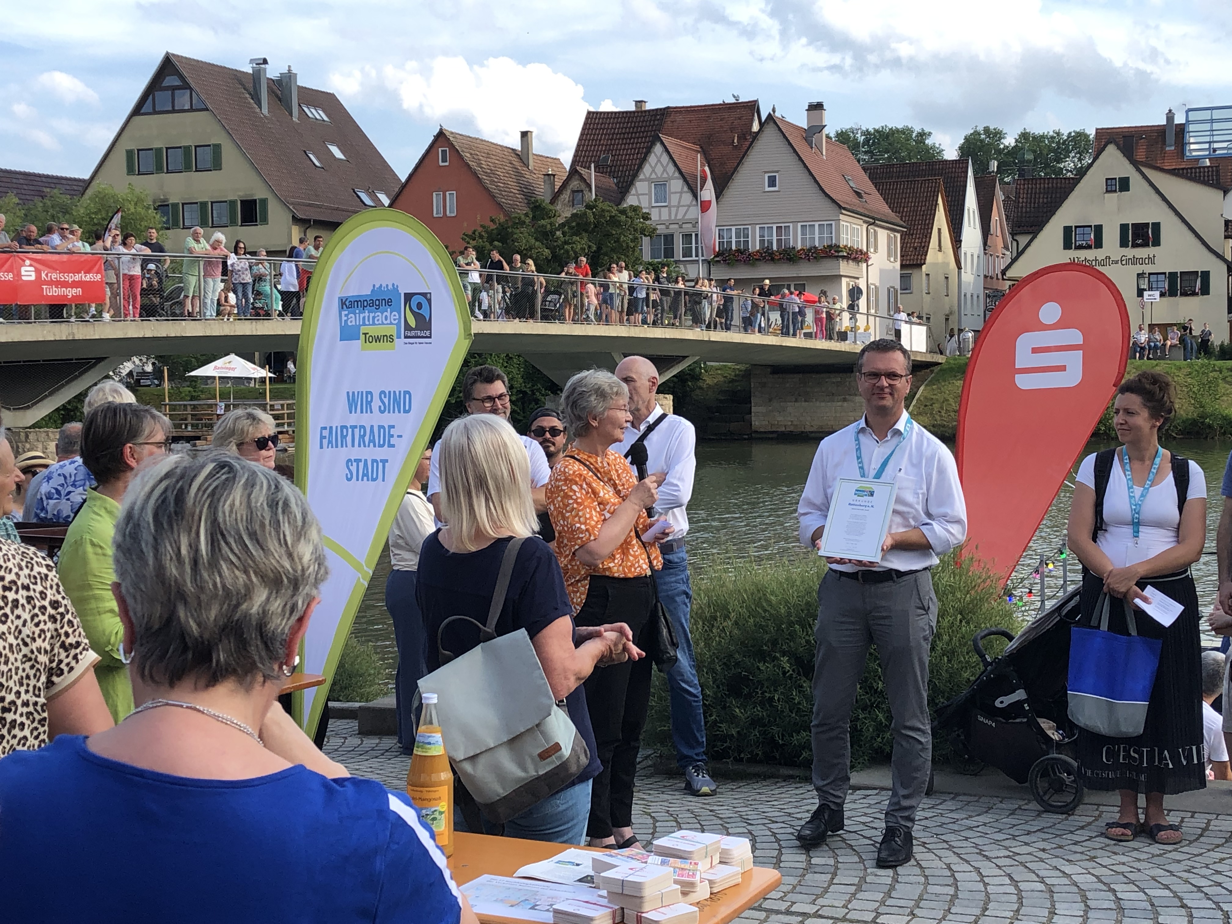 Der Bürgermeister hat eine Urkunde in der Hand mit "FairTrade Stadt Rottenburg" darauf