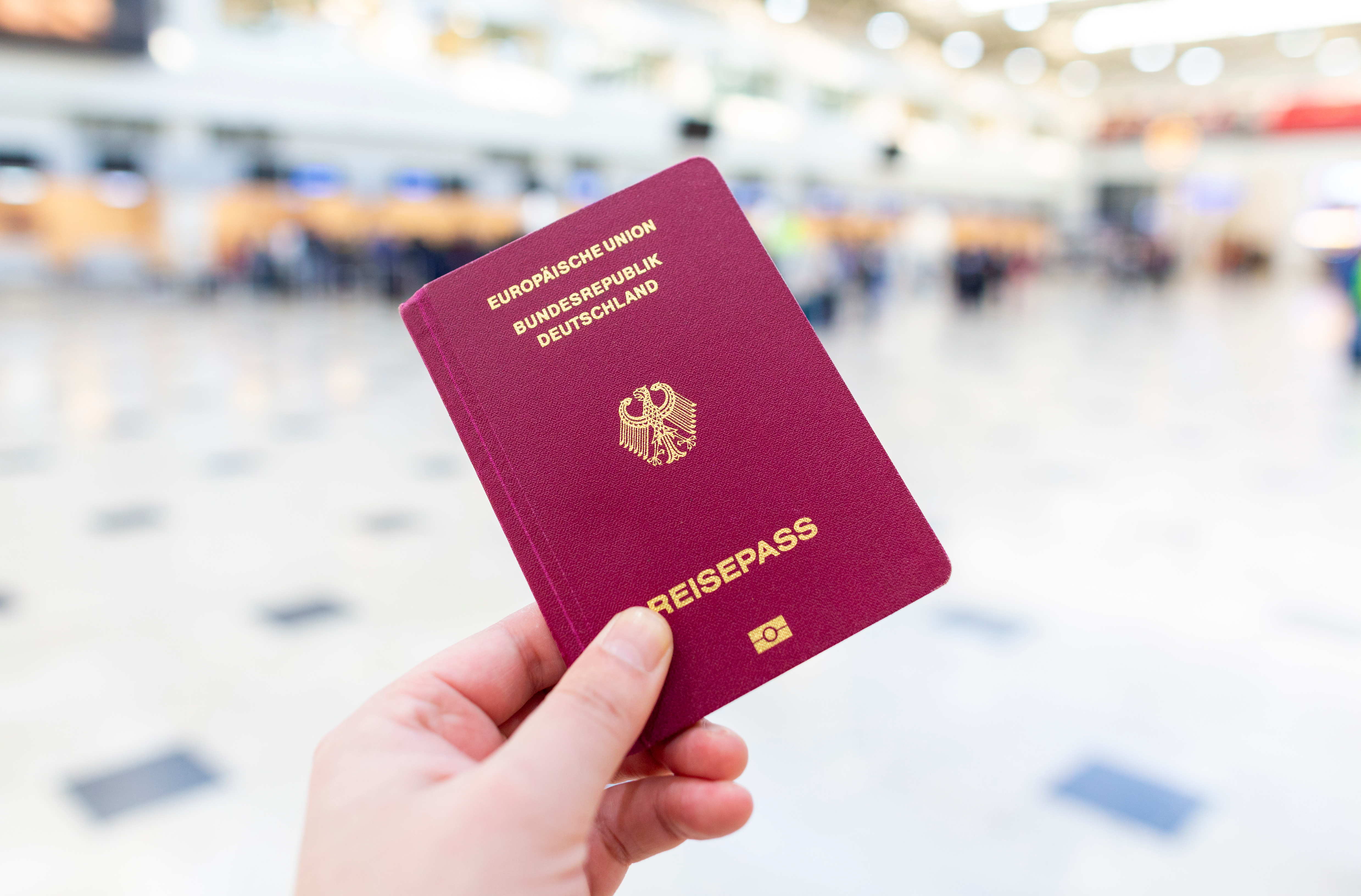 Eine Person hält einen Reisepasss hoch. 