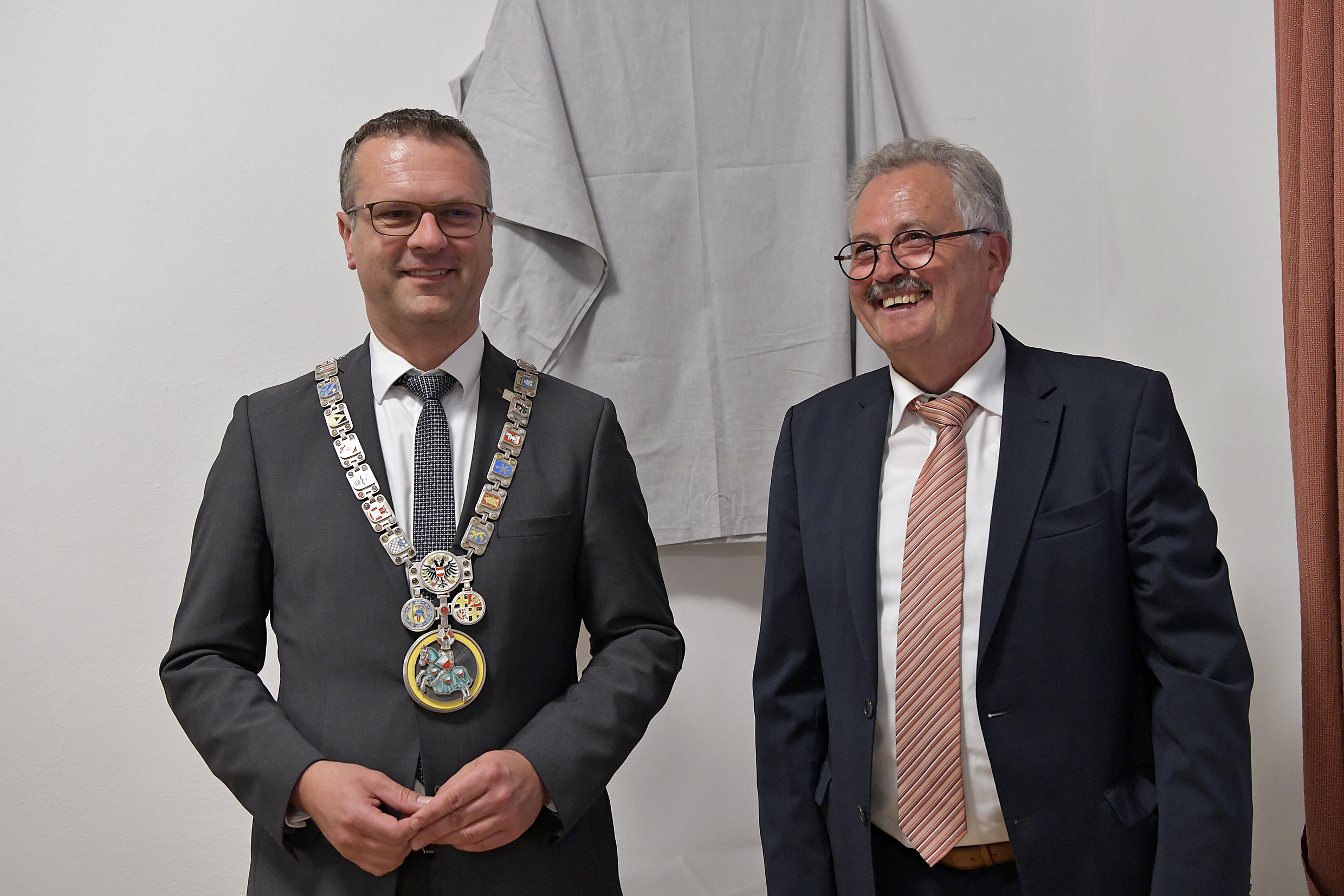 Zwei Personen stehen nebeneinander und lachen. Auf der linken Seite sieht man Oberbürgermeister Stephan Neher.
