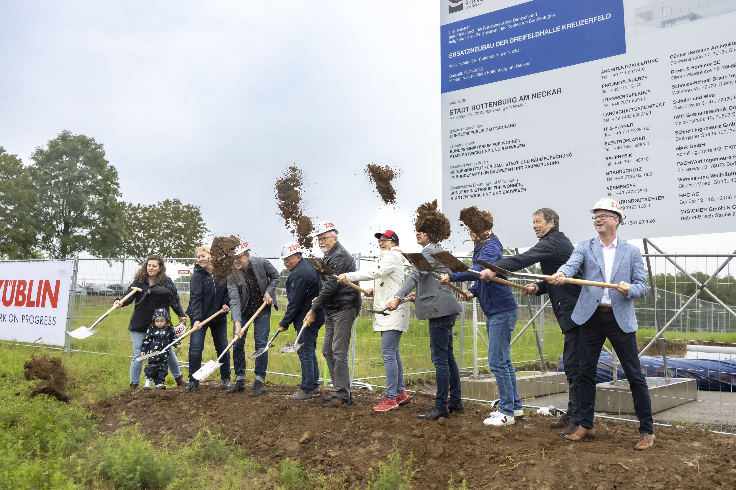 Mehrere Personen stehen in einer Reihe nebeneinander und graben symbolisch mit einem Spaten in der Erde.