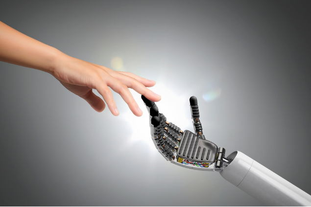 Eine normale Menschenhand und eine Hand eines Roboters berühren sich an einem Finger