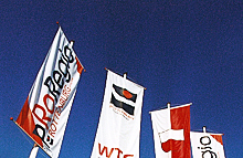 Fahnen mit Stadtlogo und Messlogo vor dem Himmel