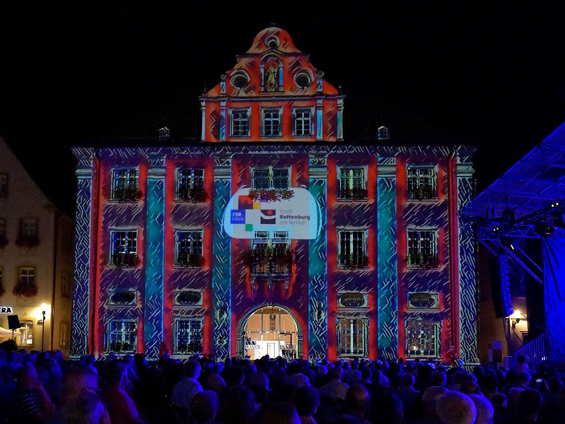 Das Rottenburger Rathaus bei Nacht. Es ist mit einer Lasershow beeuchtet.