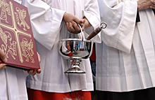 Priester mit Weihwasserkessel