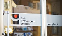 Schild auf Glas, in dem sich Häuser spiegeln 