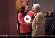 Zwei Personen, die sich die Hand geben und lachen. 