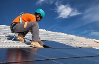Bauarbeiter auf einem Dach voller Solarplatten 