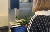 Frau steht mit dem Rücken zum Betrachter vor einem Fotoaufnahmegerät im Bürgerbüro 