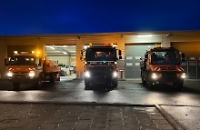 Drei Autos des Winterdienstes vor einem Gebäude 