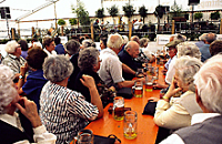 Senioren sitzen an einem Tisch und beobachten eine Veranstaltung 