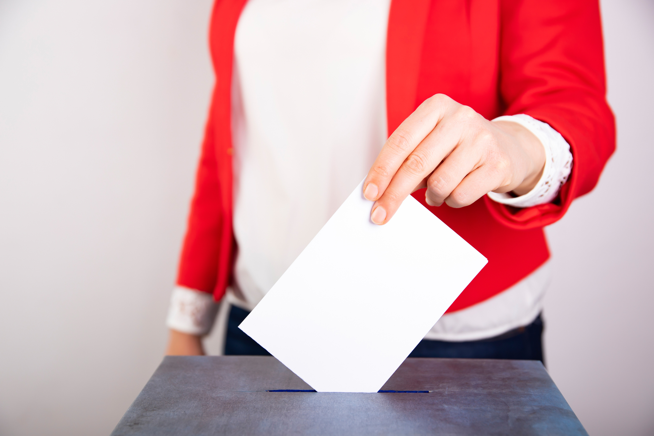 Eine Person wirft einen Wahlzettel in eine Urne