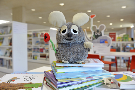 Plüschmaus auf einem Bücherstapel, im Hintergrund Bücherregale Quelle: Steffen Schlüter
