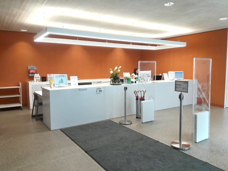 Eingangsbereich einer öffentlichen Einrichtung. Man sieht eine Empfangstheke mit entsprechender Ausstattung.  Quelle: Stadtbibliothek Rottenburg am Neckar