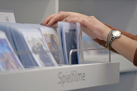 Zwei Hände greifen nach DVDs, die in einem Schubfach untergebracht sind Quelle: Steffen Schlüter