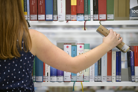 Eine Frau steht vor einem Bücherregal und greift nach einem Buch.  Quelle: Steffen Schlüter