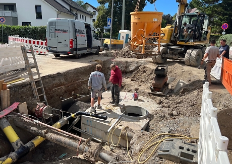 Eine aufgerissene Straße mit Absperrungen rundherum. Bauarbeiter arbeiten darin. Dahinter steht ein Kran.