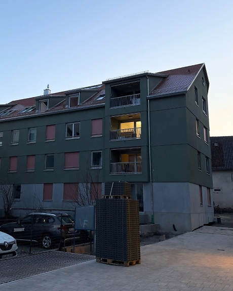 Mehrfamilienhaus in der Abenddämmerung von außen.