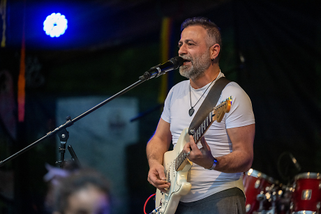 Ein Mann mit einer Gitarre auf einer Bühne am Singen