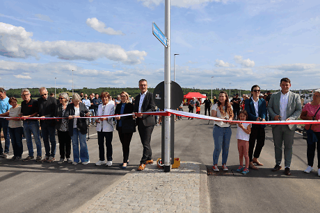 Einige Menschen schneiden auf der Straße ein Band durch, was das Gewerbegebiet eröffnet.