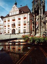 Barockes Gebäude mit gotischer Brunnensäule davor