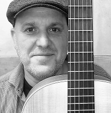 Diter Schnaas im Bild mit der Gitarre vor ihm