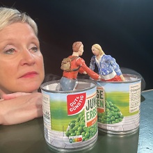 Zwei Puppen ragen aus Erbsendosen hervor.