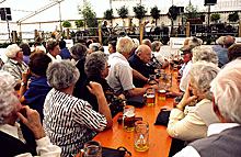 Senioren sitzen an einem Tisch und beobachten eine Veranstaltung