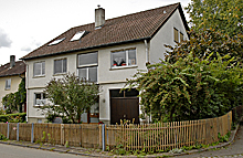 Zweistöckiges Haus, von eim Gartenzaun umgeben