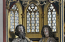 Gotisches Schnitzwerk: zwei Heilige vor Spitzbogenfenstern